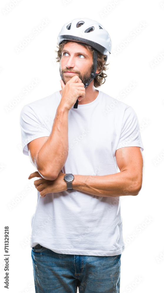 Handsome hispanic cyclist man wearing safety helmet over isolated background with hand on chin thinking about question, pensive expression. Smiling with thoughtful face. Doubt concept. Handsome hispanic cyclist man wearing safety helmet over isolated background with hand on chin thinking about question, pensive expression. Smiling with thoughtful face. Doubt concept.
