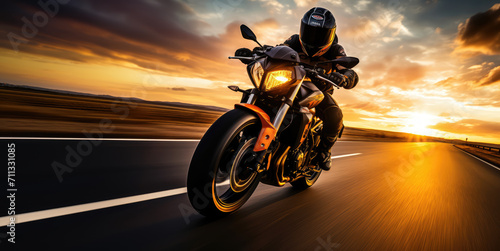 A motorcyclist rides on a highway towards the sunset, with the dynamic landscape blurring past.