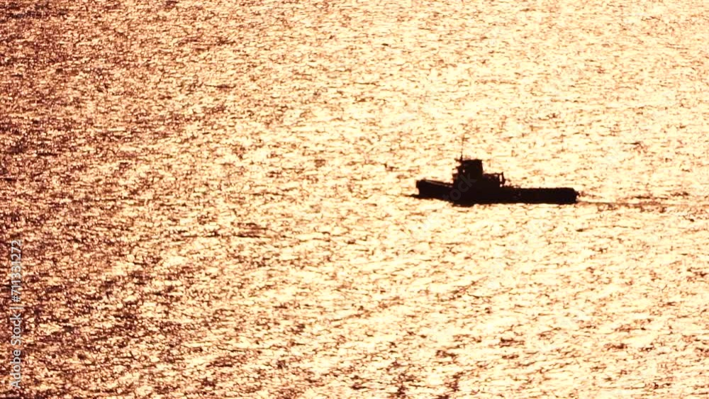 Tug boat pulls a barge loaded with harbor cranes across calm seas at ...