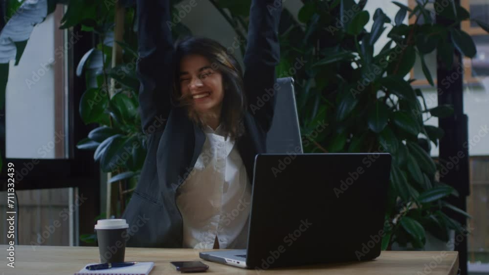 Excited happy Girl site at desk feel euphoria win online lottery. A businesswoman enjoys winning or success in business. A female freelancer works in a cafe. The woman smiles, raises her hands up Excited happy Girl site at desk feel euphoria win online lottery. A businesswoman enjoys winning or success in business. A female freelancer works in a cafe. The woman smiles, raises her hands up