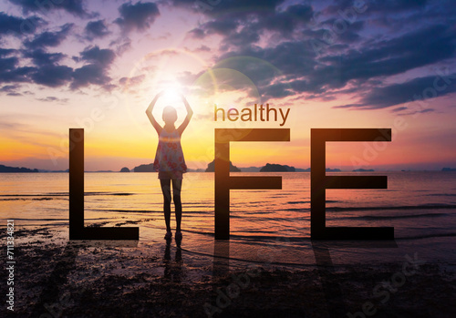 Silhouette of A girl practicing Yoga standing on tropical beach with sunset sky background, watching the sunset, standing as a part of the wording concept for healthy life. 