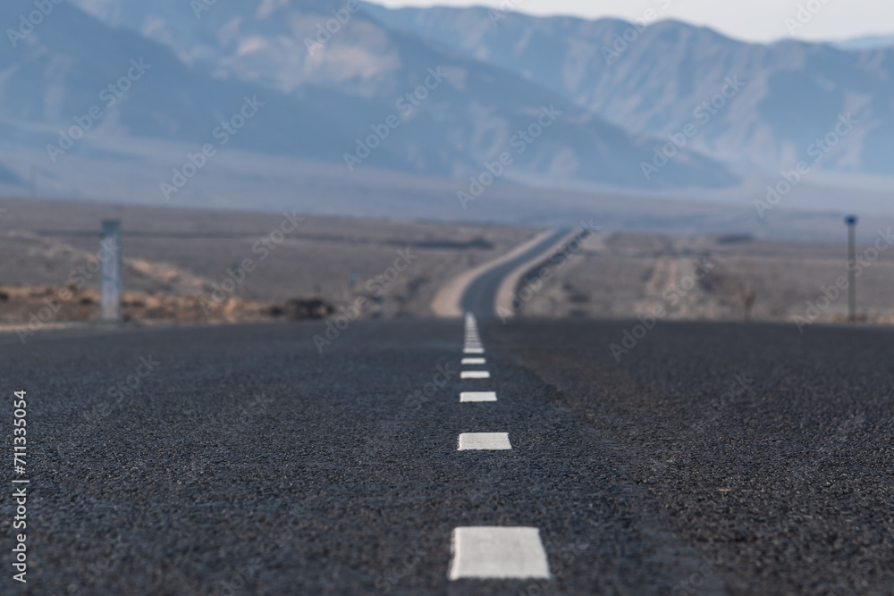 Fototapeta premium Empty asphalt road stretching beyond the horizon. Endless mountain road. Concept of road travel in Central Asia. Selective focus.