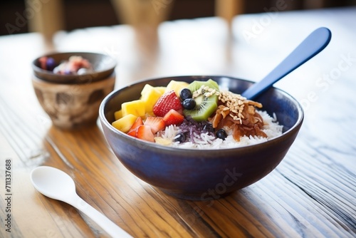 side view acai bowl on a wooden table with a spoon, napkin beside photo