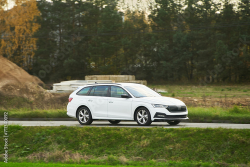 A car journey captured against the backdrop of a serene forest landscape under the enchanting light of dusk. Modern family vehicle moving on the highway. Sustainable trip.