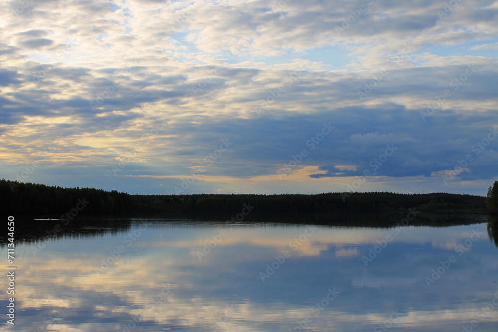 A smooth lake against the backdrop of a forest and sunset sky. Republic of Karelia. Russia.