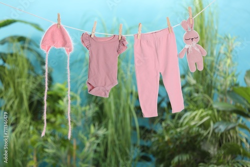 Baby clothes and bunny toy drying on laundry line outdoors