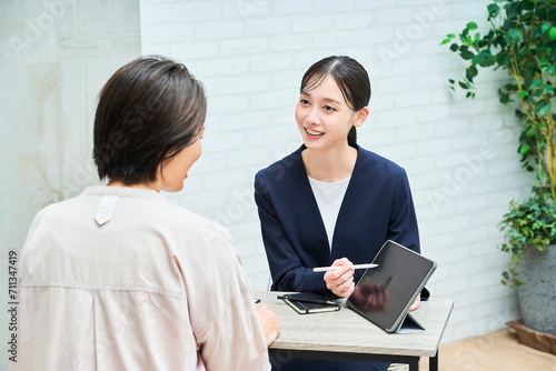 私服の女性に説明するスーツ姿の女性