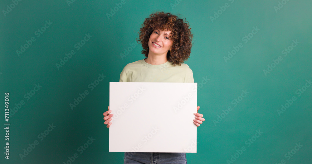 Happy woman holding blank paper in green studio Happy woman holding blank paper in green studio