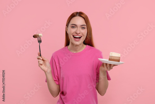 Young woman with piece of tasty cake on pink background