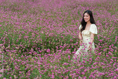 beautiful woman in dress enjoying blooming pink globe amaranth or bachelor button field
