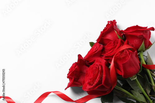 Beautiful red roses and ribbon on white background  top view. Space for text
