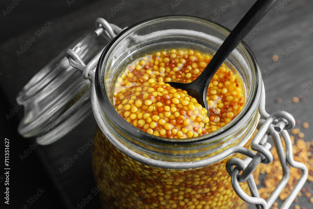 Whole grain mustard and spoon in jar on table, closeup Whole grain mustard and spoon in jar on table, closeup