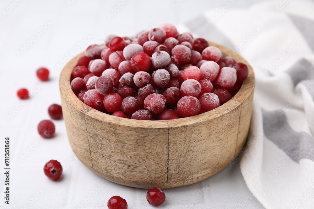 Frozen red cranberries in bowl on white tiled table, closeup Frozen red cranberries in bowl on white tiled table, closeup