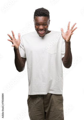 Young african american man wearing white t-shirt celebrating crazy and amazed for success with arms raised and open eyes screaming excited. Winner concept