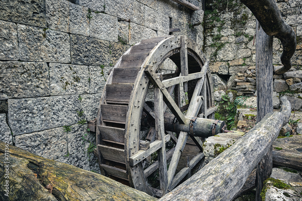 Wooden wheel of an antique water mill. Italian rural architecture, Stremiz village, Faedis, Udine province, Friuli Venezia Giulia, Italy.