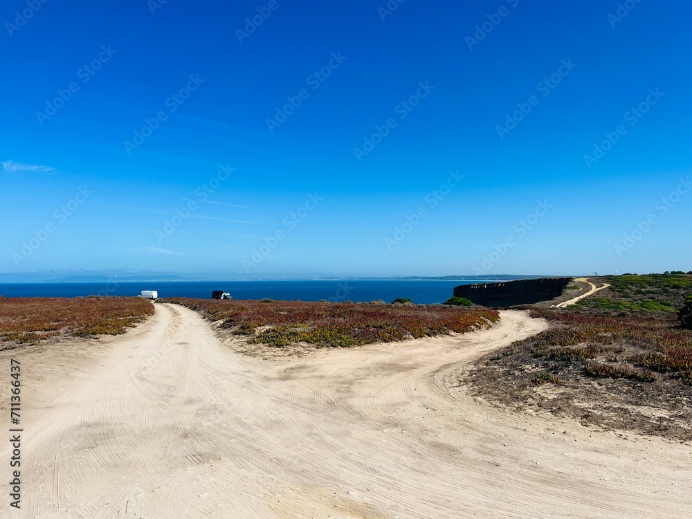 Driving ground road to the ocean, ocean road, ocean horizon, clear blue sky, white sandy ground road