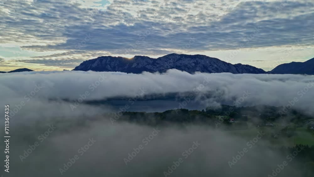 Aerial view of fog moving over the green nature in Austria during sunset. Aerial view of fog moving over the green nature in Austria during sunset.