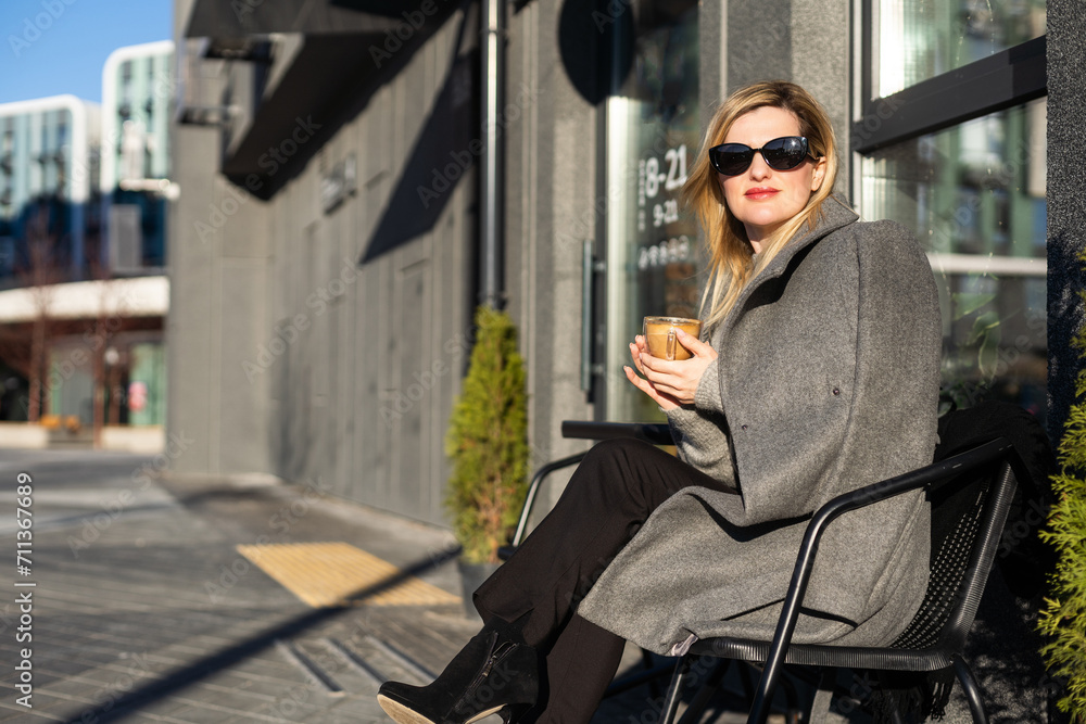 Young caucasian woman business woman drinks coffee at coffee shop terrace