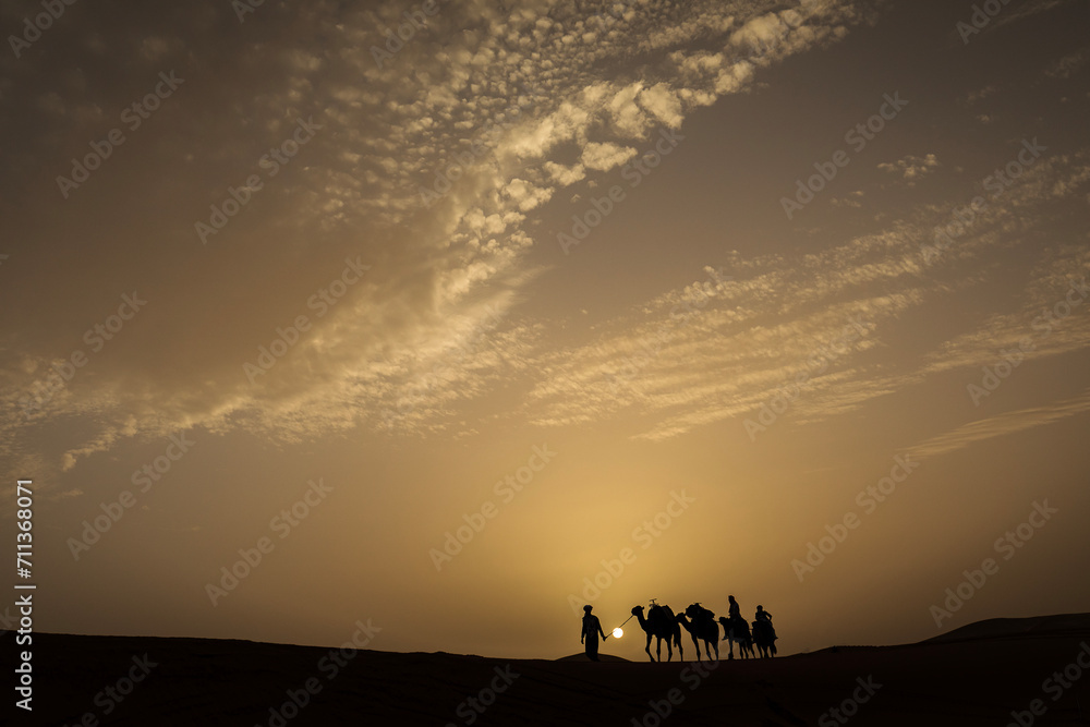 Silhouette of camel caravan with beautiful clouds in background in Sahara, Merzouga, Morocco