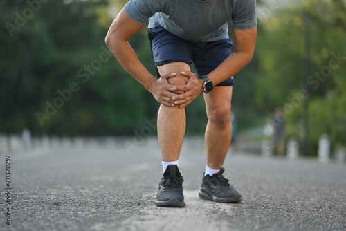 Male athlete suffering ligament injury during running workout, training. Sport and health care concept