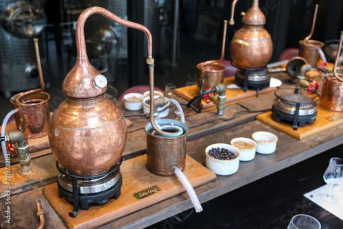 Small copper stills and distilling equipment arranged on a decorated table. photo