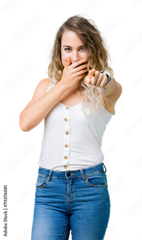 Beautiful young blonde woman over isolated background Laughing of you, pointing to the camera with finger hand over mouth, shame expression Beautiful young blonde woman over isolated background Laughing of you, pointing to the camera with finger hand over mouth, shame expression