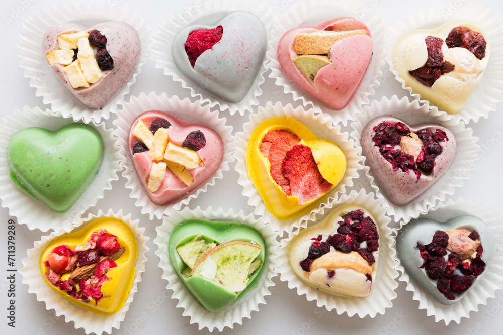 chocolate sweets in the form of a heart with fruits and nuts on a colored background. top view with space for text, holiday concept chocolate sweets in the form of a heart with fruits and nuts on a colored background. top view with space for text, holiday concept