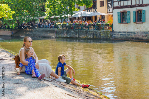 A happy family relaxes on the river bank. Alsace, France. Traditional half-timbered houses on the canals district La Petite France in Strasbourg in summer. photo