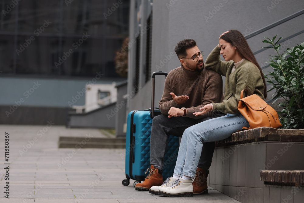 Being late. Worried couple sitting on bench outdoors, space for text