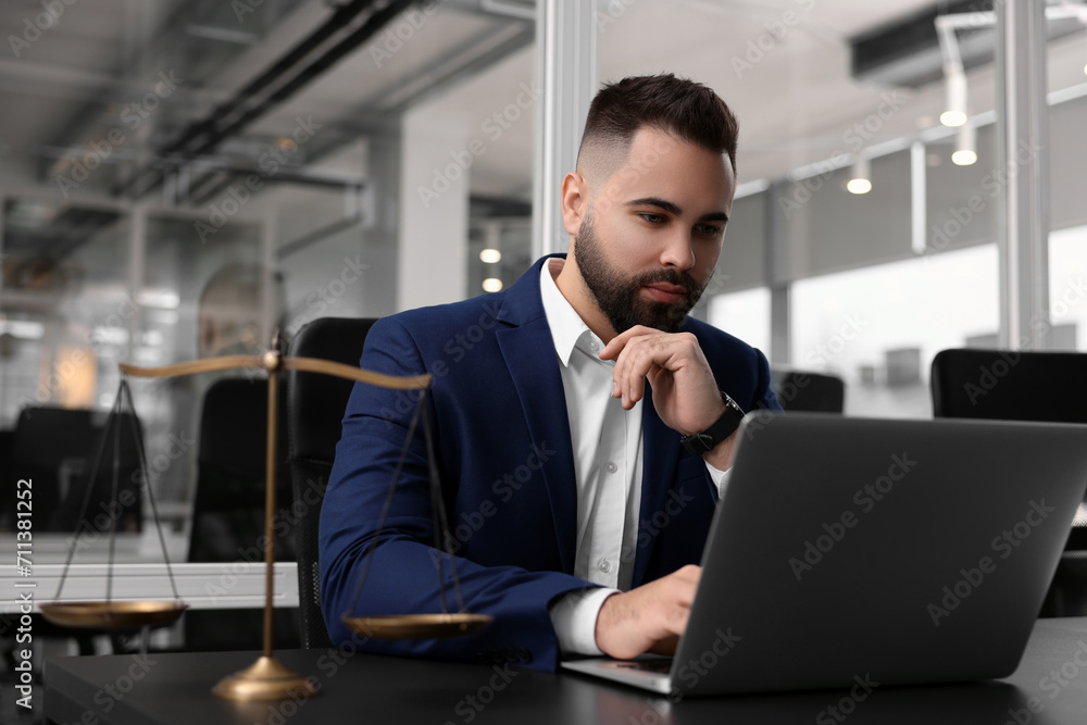 Serious lawyer working with laptop at table in office Serious lawyer working with laptop at table in office