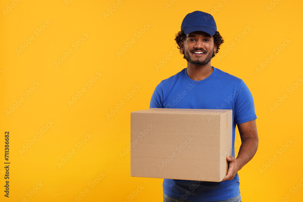 Happy courier with parcel on orange background, space for text Happy courier with parcel on orange background, space for text