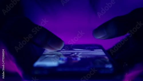 Finger of woman touching scroll page app on mobile phone.In a room with blue and purple neon tones.concept Social media and marketing photo