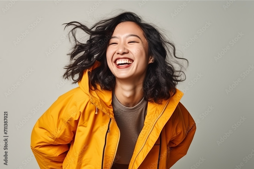 Portrait of a happy young asian woman laughing over gray background Portrait of a happy young asian woman laughing over gray background