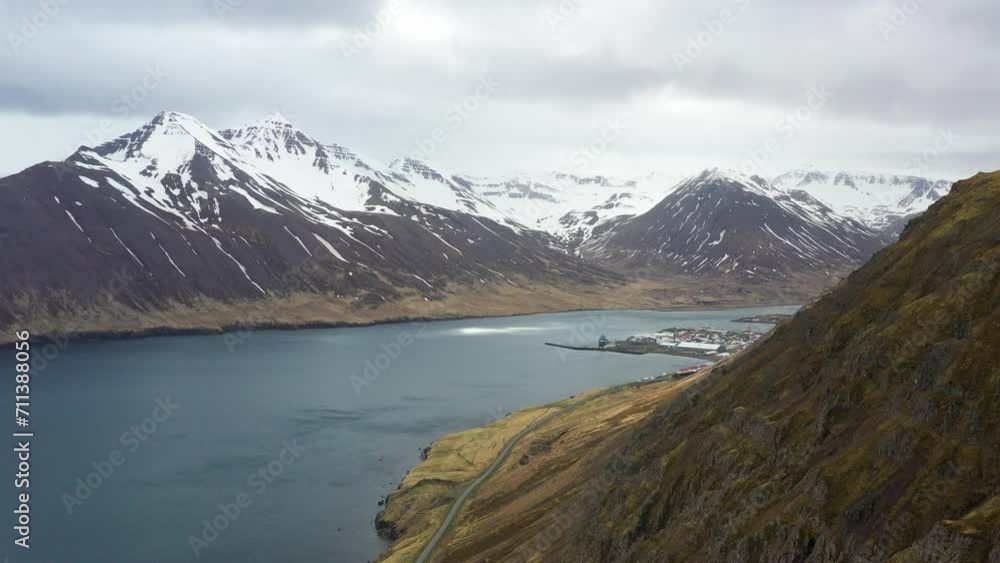 Aerial view of a serene Icelandic fjord with snow-capped mountains and a coastal village Aerial view of a serene Icelandic fjord with snow-capped mountains and a coastal village