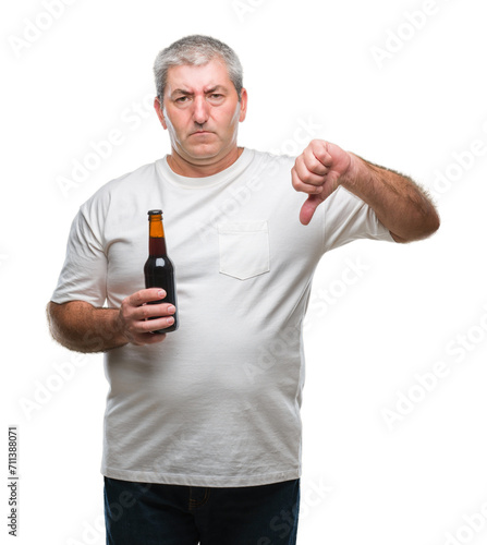 Handsome senior man drinking beer bottle over isolated background with angry face, negative sign showing dislike with thumbs down, rejection concept