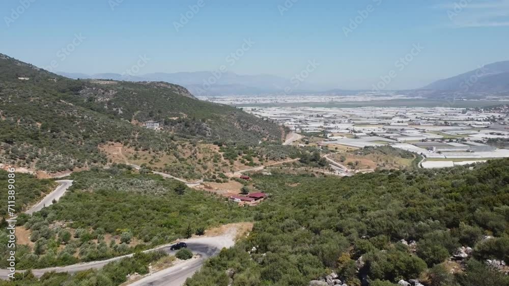 Zipline drone shot revealing a winding road and a modern Turkish town at the foot of the mountains at Fethiye, Turkey. Zipline drone shot revealing a winding road and a modern Turkish town at the foot of the mountains at Fethiye, Turkey.