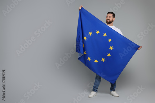 Man holding European Union flag on light grey background, space for text