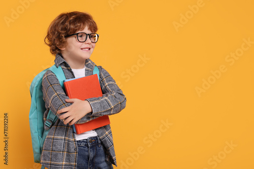 Foto Happy schoolboy with backpack and books on orange background, space for text
