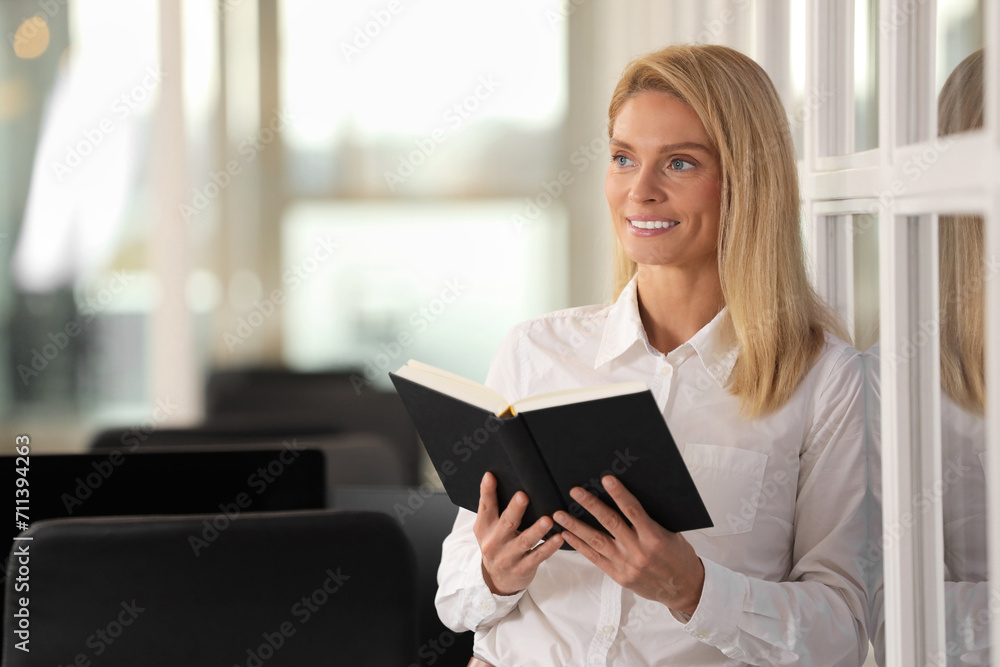 Smiling woman with book in office, space for text. Lawyer, businesswoman, accountant or manager Smiling woman with book in office, space for text. Lawyer, businesswoman, accountant or manager