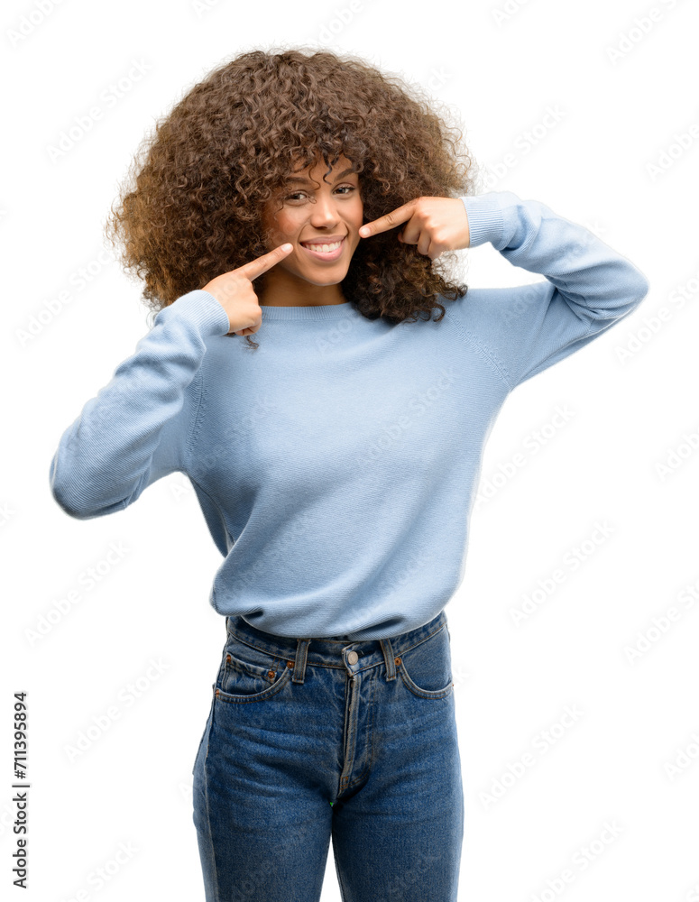 African american woman wearing a sweater smiling confident showing and pointing with fingers teeth and mouth. Health concept. African american woman wearing a sweater smiling confident showing and pointing with fingers teeth and mouth. Health concept.