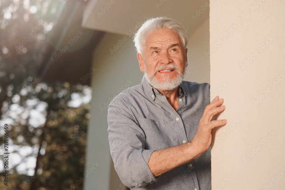 Portrait of senior man near house outdoors, space for text. Annoying neighbour Portrait of senior man near house outdoors, space for text. Annoying neighbour