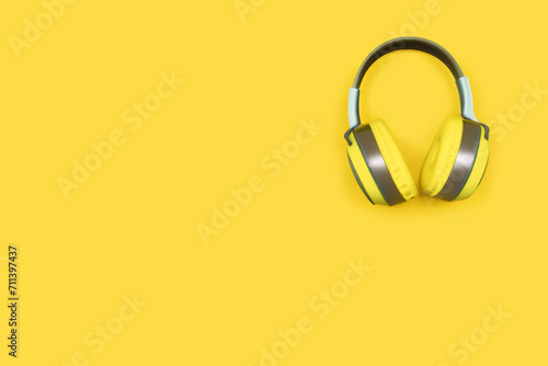 musical composition. gray-yellow headphones lie on a yellow background, top view, creative concept