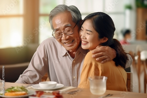 Tender Kitchen Moment: Asian Daughter Hugging Father Affectionately as He Prepares Food.