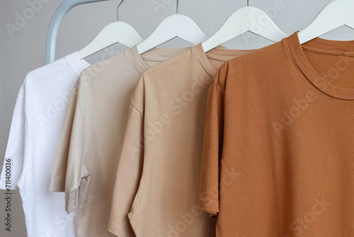 T-shirts of brown colors variant on white hanger displayed on a white clothes rack