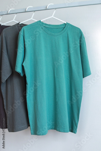 Plain tosca cotton t-shirt mockup hanging on white rack hanger, front view