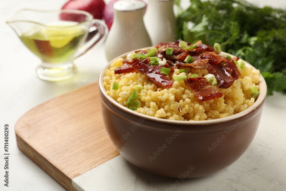 Tasty millet porridge with bacon and green onion in bowl on table, closeup Tasty millet porridge with bacon and green onion in bowl on table, closeup