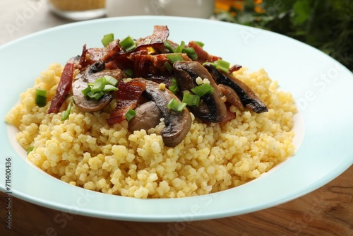Tasty millet porridge with mushrooms, bacon and green onion on table, closeup