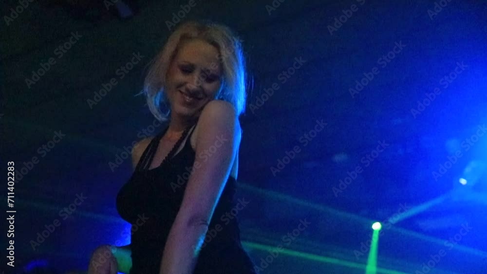 Dimly lit disco club, a beautiful woman is shown dancing to modern dance in slow motion under green strobe laser lights. Adult lifestyle scene in nightlife and entertainment. Dimly lit disco club, a beautiful woman is shown dancing to modern dance in slow motion under green strobe laser lights. Adult lifestyle scene in nightlife and entertainment.
