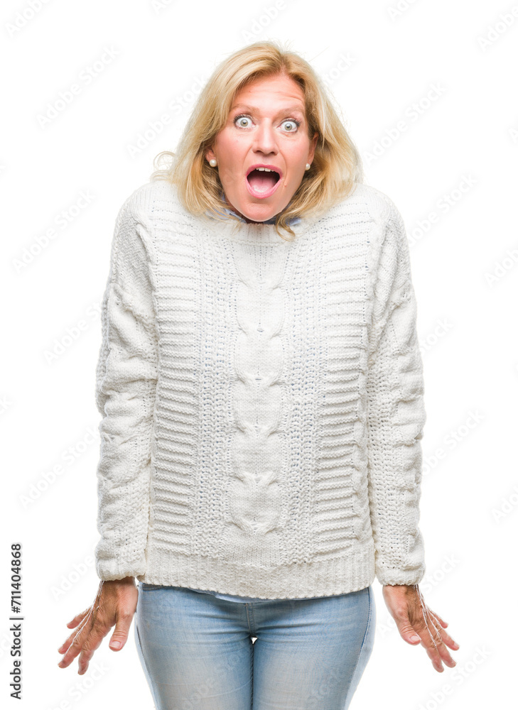 Middle age blonde woman wearing winter sweater over isolated background afraid and shocked with surprise expression, fear and excited face. Middle age blonde woman wearing winter sweater over isolated background afraid and shocked with surprise expression, fear and excited face.