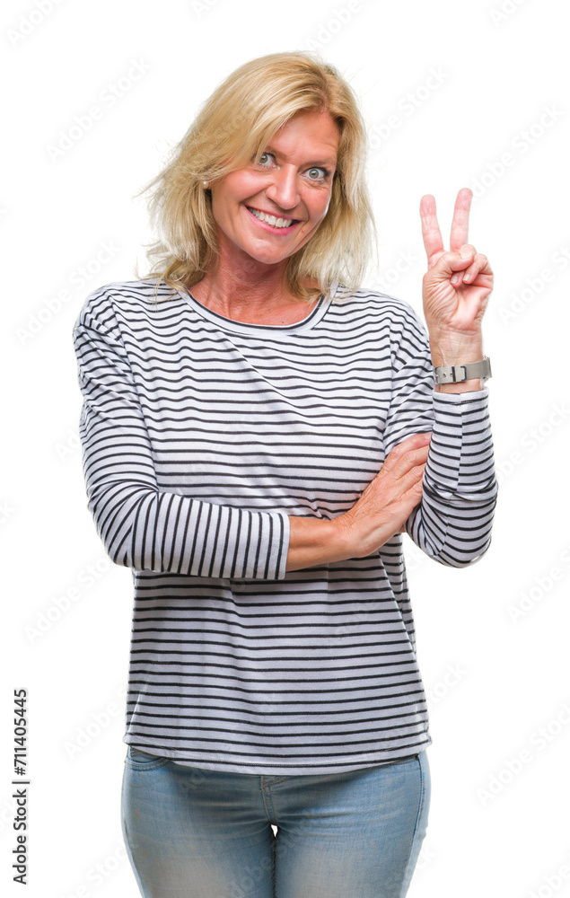Middle age blonde woman over isolated background smiling with happy face winking at the camera doing victory sign. Number two. Middle age blonde woman over isolated background smiling with happy face winking at the camera doing victory sign. Number two.